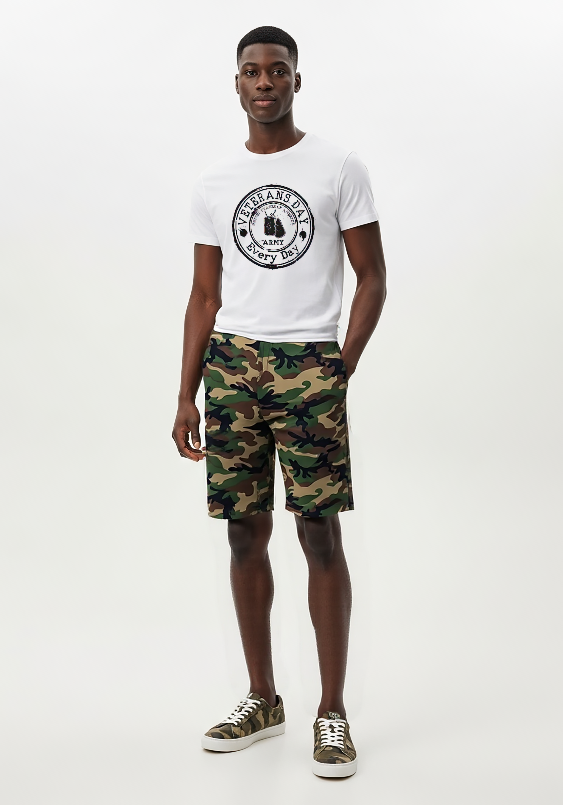 Black man wearing a white t-shirt with Veterans Day Every Day text and camouflage shorts on a white background